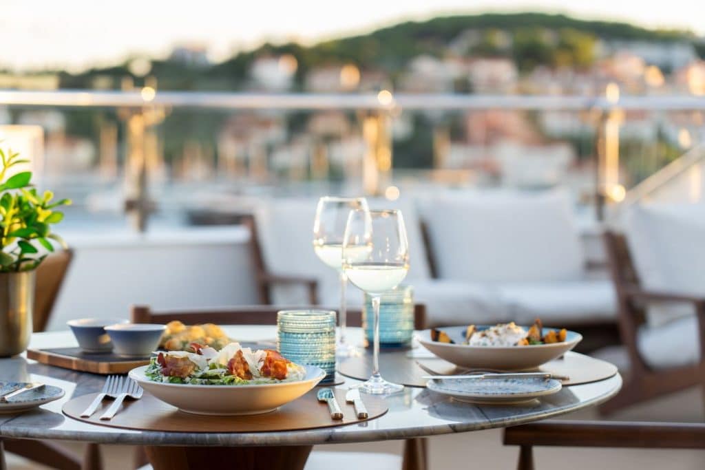 Outdoor dining at Mistral aboard Luminara with coastal views