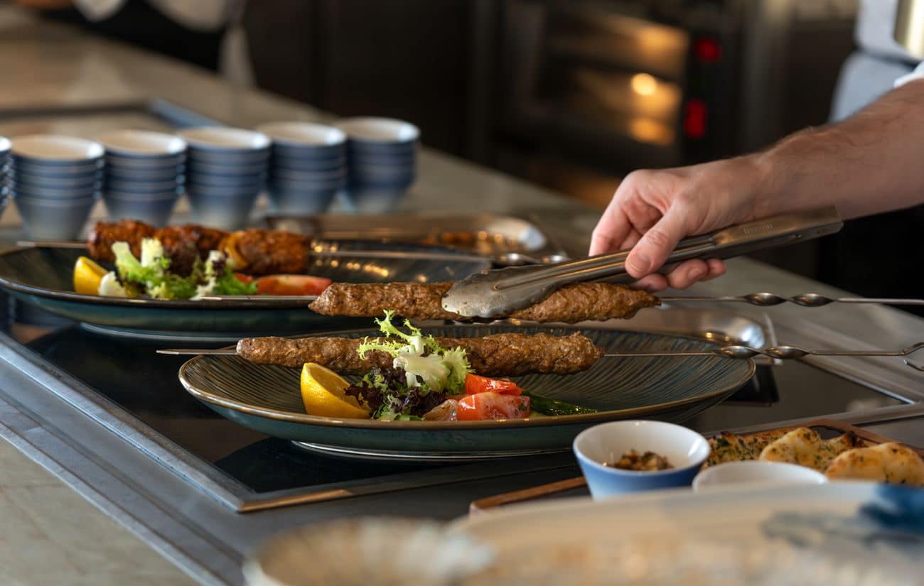 Chef plating grilled skewers with vegetables at The Grill