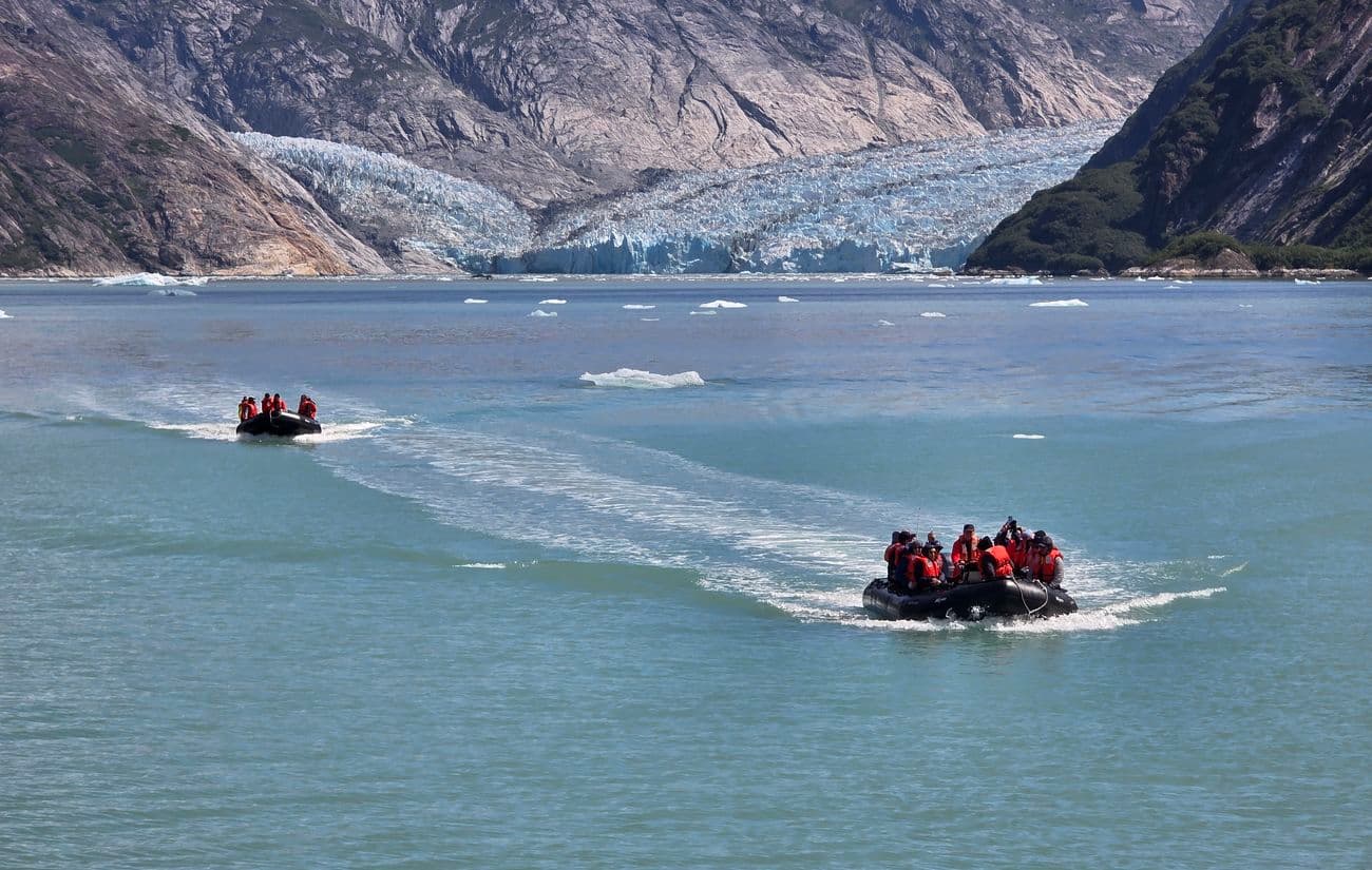 Zodiac boats carrying guests toward a glacier in Alaska